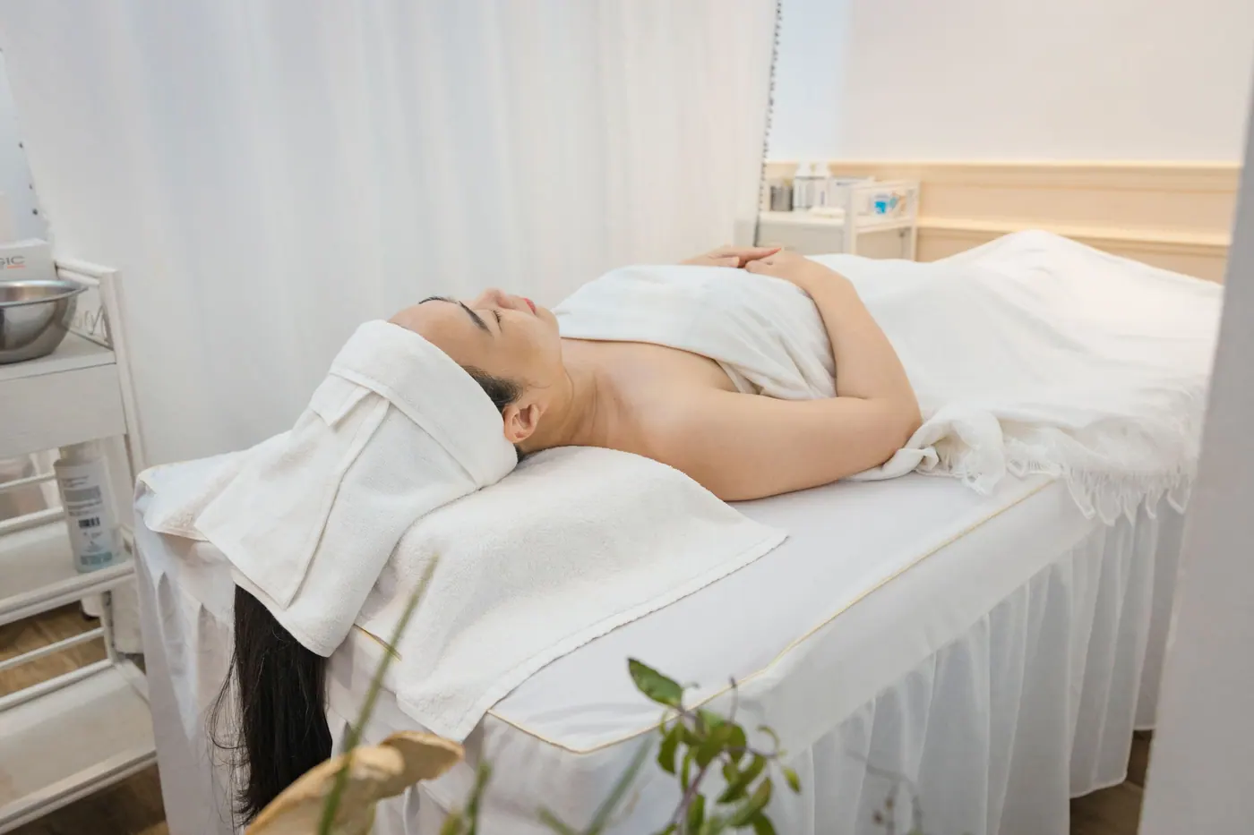 A client resting on a white treatment bed in a bright, calm room